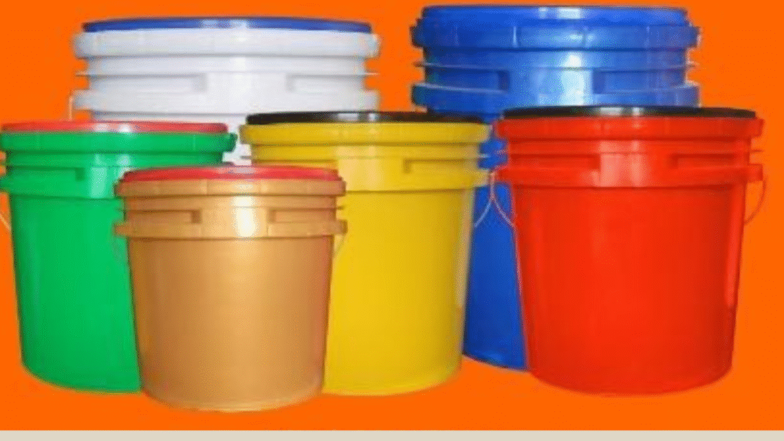 Multiple large plastic buckets in various colors—green, brown, yellow, red, blue, and white—are arranged together against a bright orange background. Each bucket has a matching or contrasting lid and industrial-style design."